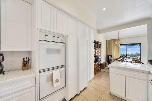 kitchen with white cabinets, tasteful backsplash, tile countertops, and white double oven
