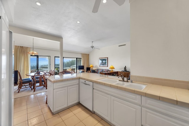 kitchen featuring tile counters, ceiling fan, dishwasher, and a sink