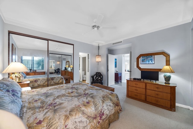 bedroom with light colored carpet, visible vents, ceiling fan, baseboards, and ensuite bath