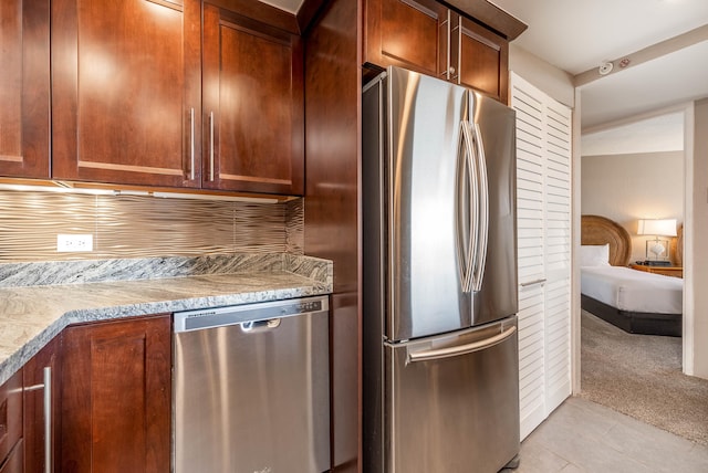 kitchen with stainless steel appliances, light stone countertops, and light carpet