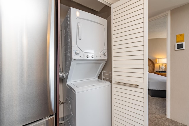 laundry area featuring carpet and stacked washer / dryer