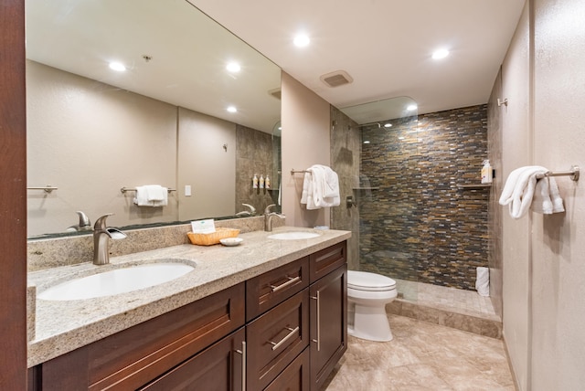 bathroom with vanity, toilet, and tiled shower