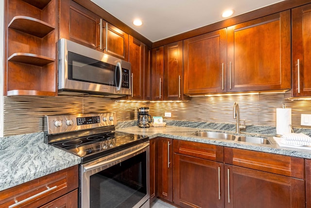 kitchen with light stone countertops, sink, backsplash, and appliances with stainless steel finishes