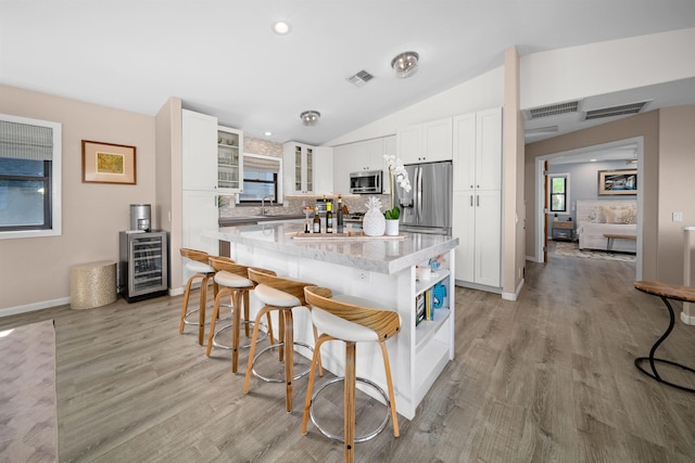 kitchen with visible vents, glass insert cabinets, beverage cooler, appliances with stainless steel finishes, and white cabinetry