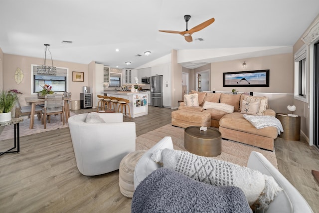 living room with visible vents, lofted ceiling, a ceiling fan, and light wood finished floors