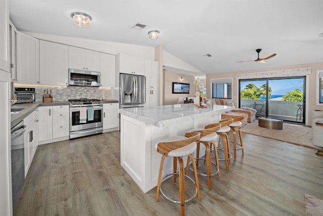 kitchen with visible vents, backsplash, a center island, lofted ceiling, and stainless steel appliances