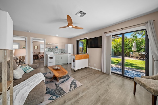 living room with light wood-style flooring, baseboards, visible vents, and ceiling fan