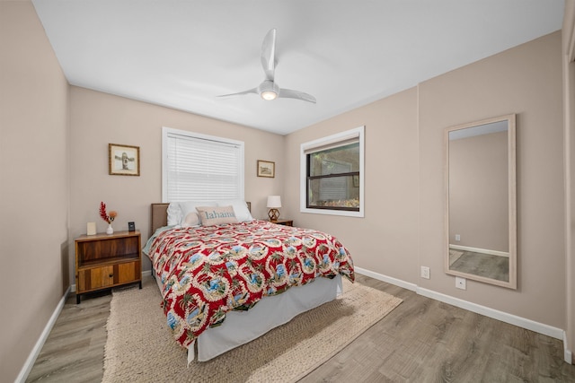 bedroom with a ceiling fan, baseboards, and light wood-type flooring