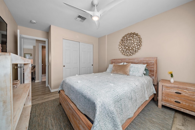 bedroom featuring visible vents, wood finished floors, a closet, baseboards, and ceiling fan