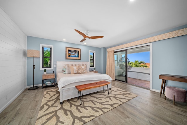 bedroom with wood finished floors, multiple windows, access to exterior, and wood walls