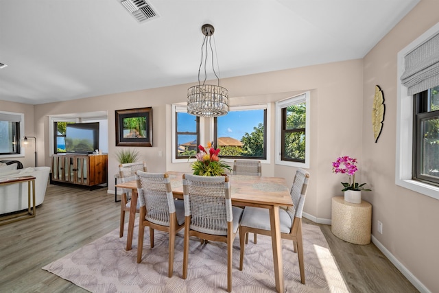 dining space with visible vents, baseboards, an inviting chandelier, and light wood finished floors