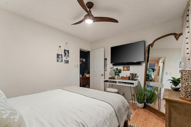 1299 Uluniu Rd Unit 103E, Kihei, HI 96753 - bedroom with light wood-type flooring, a textured ceiling, and a ceiling fan