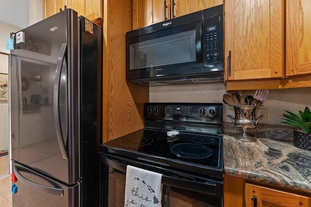 1299 Uluniu Rd Unit 103E, Kihei, HI 96753 - kitchen with black appliances, dark stone countertops, and brown cabinets