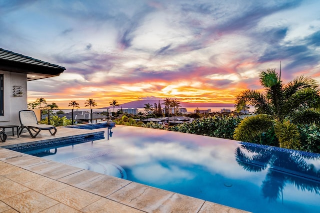 pool at dusk featuring a patio