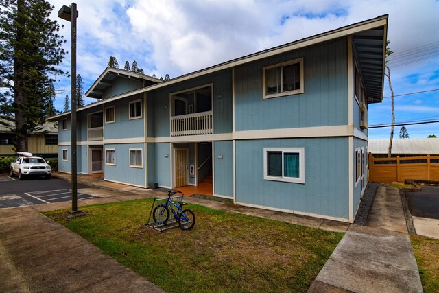 view of front of home with a balcony and a front yard