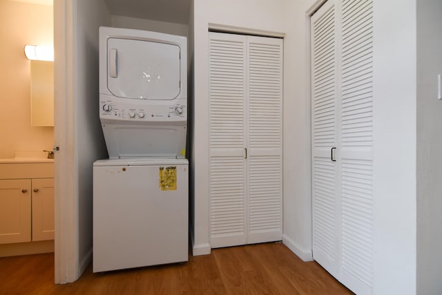 washroom with light hardwood / wood-style flooring and stacked washer / drying machine