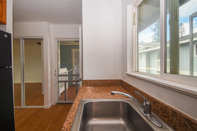 kitchen featuring sink, wood-type flooring, and black fridge