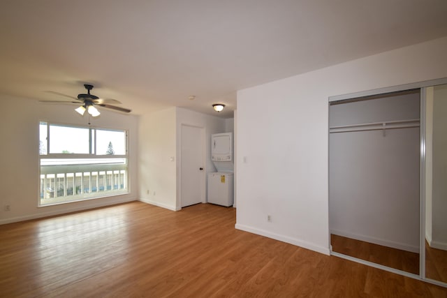 unfurnished bedroom with ceiling fan, light hardwood / wood-style flooring, a closet, and stacked washer and dryer