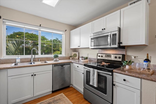 22 Kai Makani Loop Unit 201, Kihei, HI 96753 - kitchen featuring appliances with stainless steel finishes, a sink, white cabinets, and light wood finished floors