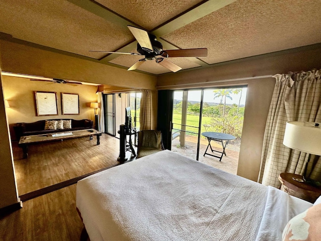 bedroom with vaulted ceiling, a textured ceiling, access to outside, hardwood / wood-style flooring, and ceiling fan