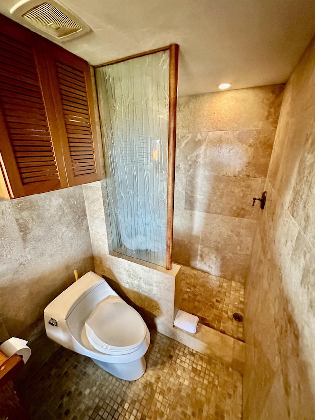 bathroom with toilet, tile patterned flooring, and tile walls