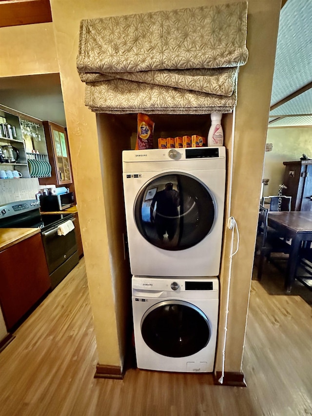 washroom featuring stacked washer / dryer and hardwood / wood-style flooring