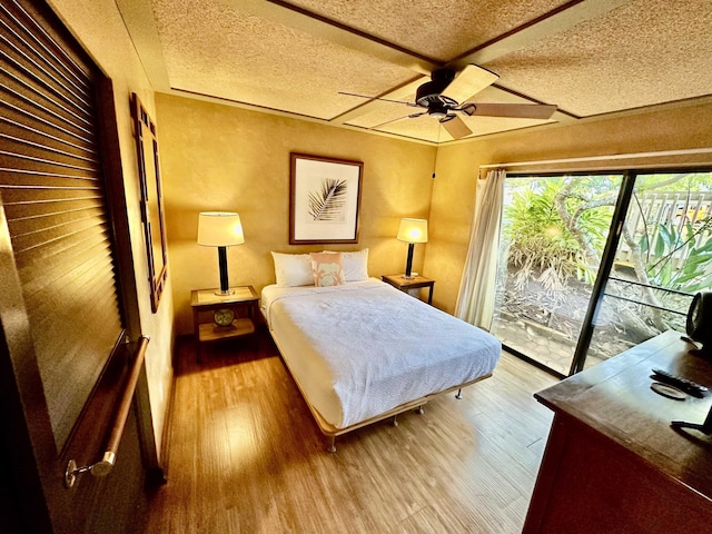 bedroom featuring ceiling fan, light hardwood / wood-style floors, a textured ceiling, and access to outside