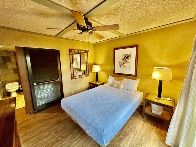 bedroom with hardwood / wood-style flooring, ceiling fan, and a textured ceiling