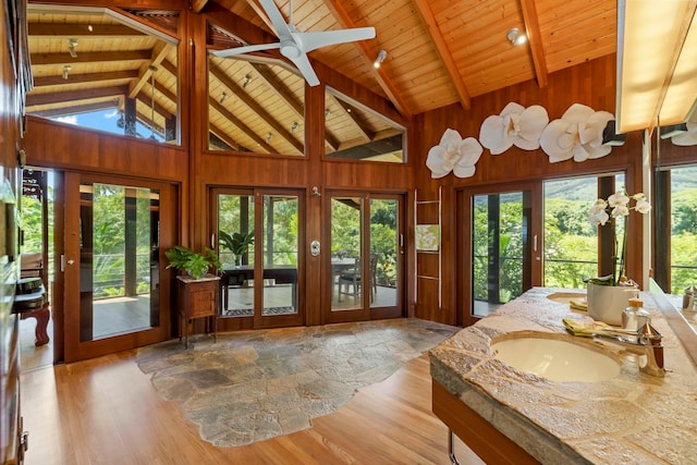 sunroom featuring lofted ceiling with beams, plenty of natural light, sink, and wooden ceiling