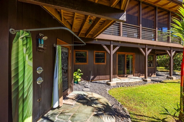 view of exterior entry with a yard and a patio area