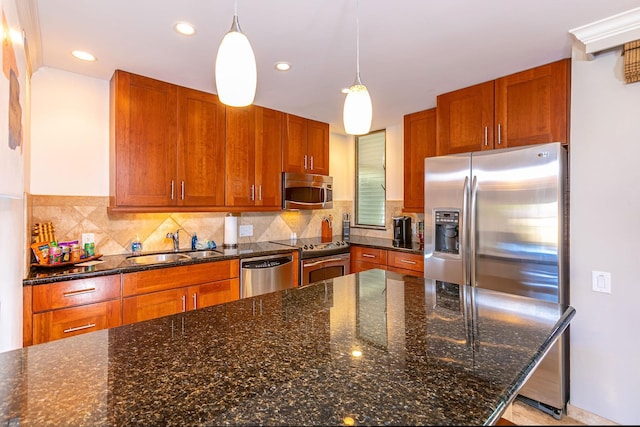 kitchen with backsplash, dark stone counters, sink, hanging light fixtures, and stainless steel appliances