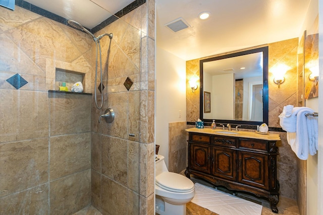 bathroom featuring tile patterned flooring, vanity, toilet, and tile walls