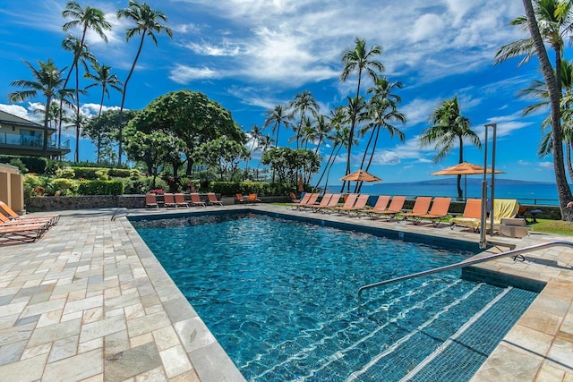 view of pool with a water view and a patio