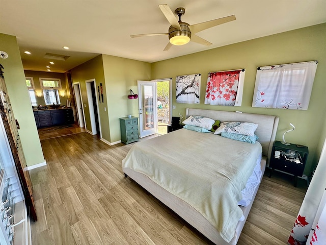 bedroom featuring ceiling fan, light hardwood / wood-style floors, and multiple windows