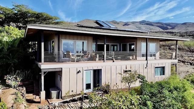 rear view of property featuring a balcony, a mountain view, and solar panels