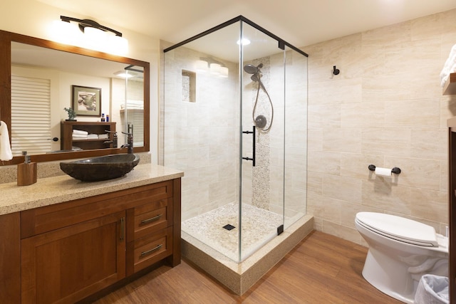 bathroom with walk in shower, vanity, tile walls, hardwood / wood-style floors, and toilet