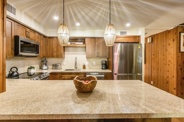 kitchen featuring decorative backsplash, sink, stainless steel appliances, and decorative light fixtures