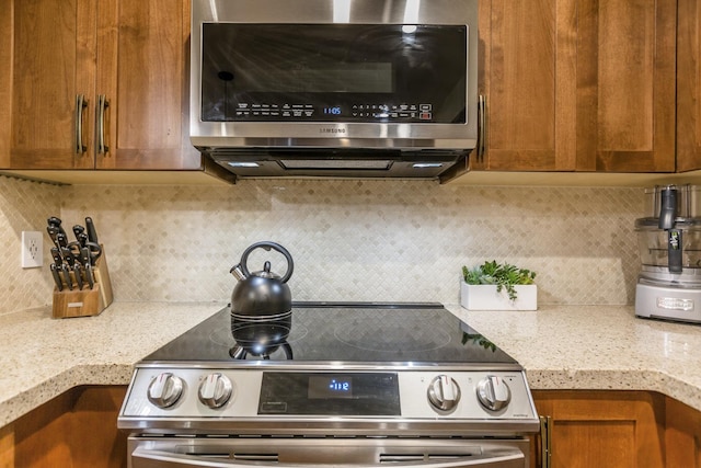 interior space featuring light stone countertops, backsplash, and stainless steel appliances