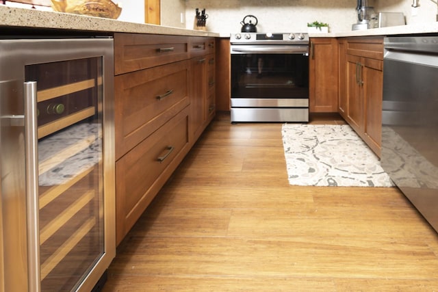 kitchen featuring decorative backsplash, light hardwood / wood-style flooring, beverage cooler, and appliances with stainless steel finishes