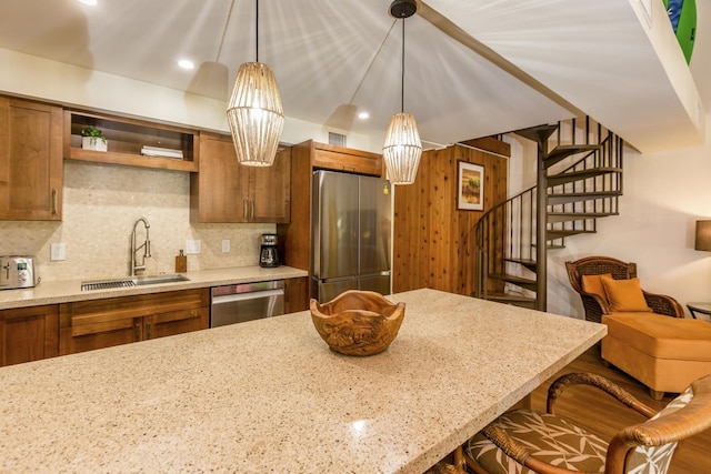 kitchen with sink, hanging light fixtures, a kitchen breakfast bar, light stone counters, and appliances with stainless steel finishes