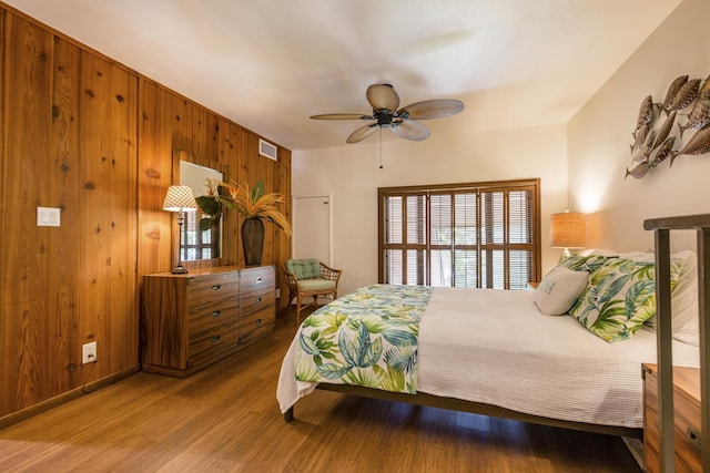 bedroom featuring light hardwood / wood-style floors, ceiling fan, and wooden walls