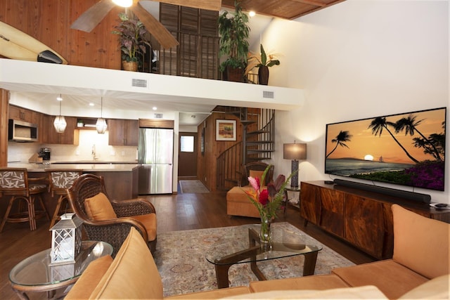 living room featuring ceiling fan, sink, a towering ceiling, and dark hardwood / wood-style floors