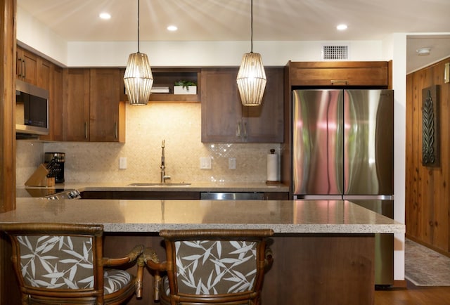 kitchen with decorative backsplash, decorative light fixtures, stainless steel appliances, and sink