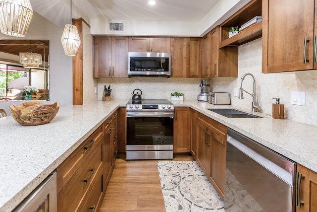 kitchen with sink, hanging light fixtures, tasteful backsplash, light stone counters, and stainless steel appliances