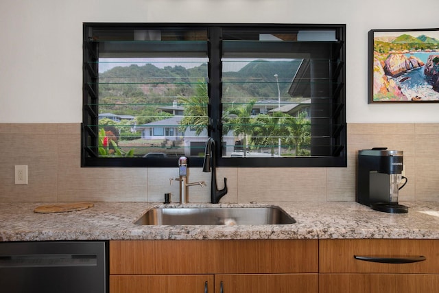 kitchen featuring black dishwasher, light stone counters, tasteful backsplash, and sink