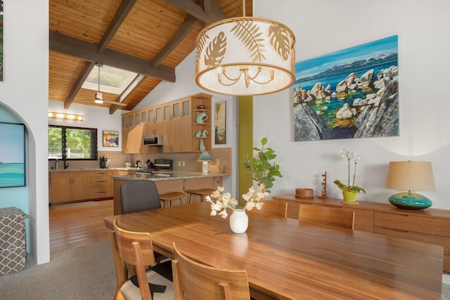 dining room featuring a notable chandelier, light hardwood / wood-style flooring, lofted ceiling with skylight, and wood ceiling