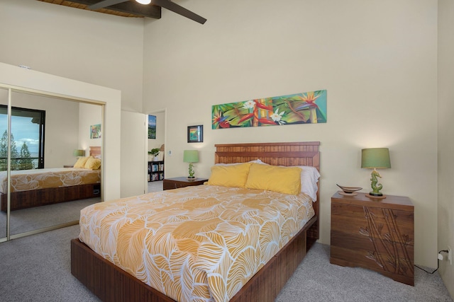 carpeted bedroom with ceiling fan, a closet, a towering ceiling, and beam ceiling