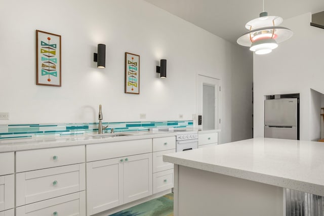 kitchen with a center island, white cabinets, hanging light fixtures, light stone countertops, and stainless steel fridge