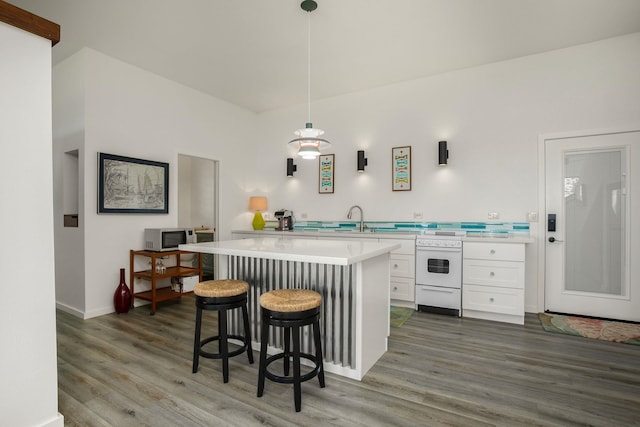 kitchen featuring wood-type flooring, sink, white cabinetry, a kitchen bar, and hanging light fixtures