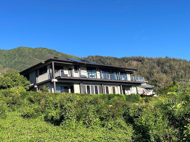 rear view of property featuring a balcony and a mountain view